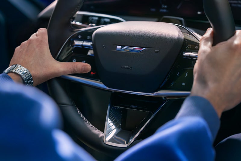Close-up of a Man About to Press the V-Button on the 2026 OPTIQ-V Steering Wheel | Stadium Cadillac in Salem OH